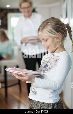 Lächelnde Mädchen Holding Platten in Küche Stockfoto