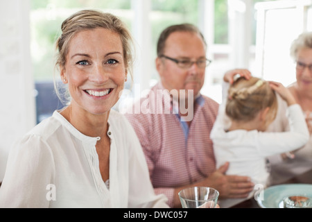 Porträt der lächelnde Frau mit Familie am Esstisch sitzen Stockfoto