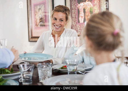 Lächelnde Frau mit Mittagessen mit der Familie am Esstisch Stockfoto