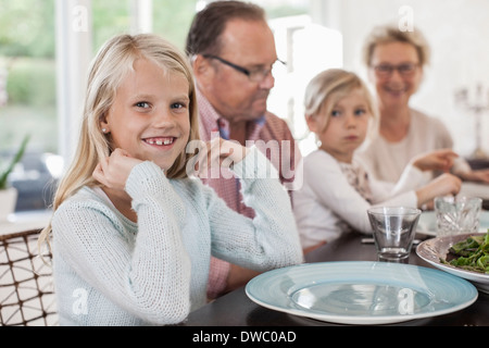 Porträt von glücklichen Mädchen sitzen mit Familie am Esstisch Stockfoto