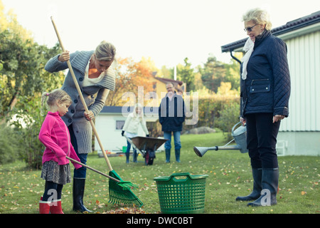 Mehr-Generationen-Familie Rechen Herbst fährt um Hof Stockfoto