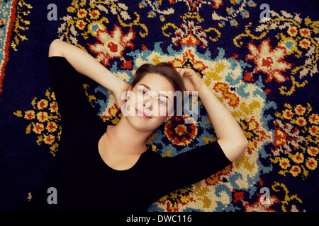 Porträt der jungen Frau liegt auf gemusterten Teppich Stockfoto