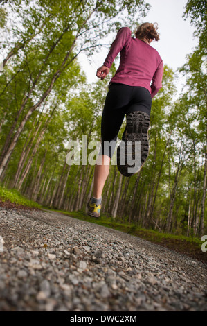 Frau auf einem Schotterweg durch den Wald laufen Stockfoto