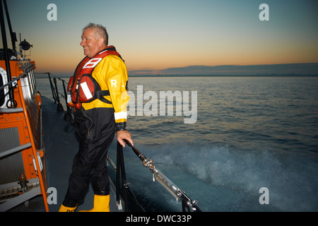 Porträt von reifer Mann hält Rettungsboot Geländer auf hoher See Stockfoto