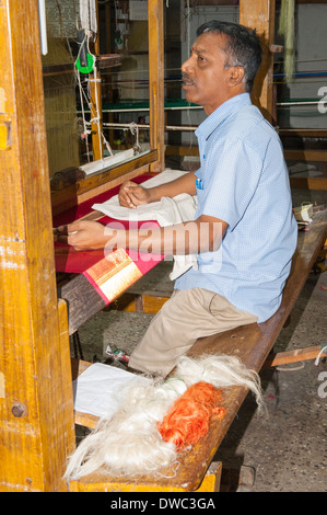 Indien Tamil Nadu Kanchipuram factory workshop Mann Mann im blauen Hemd Holz- Webstuhl roter Seide tuch Thema damen Sari Sari gold Kleidung Stockfoto