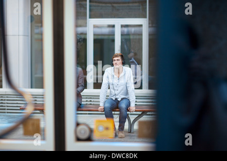 Junger Mann sitzt auf dem Zug Bahnhof Bank Stockfoto