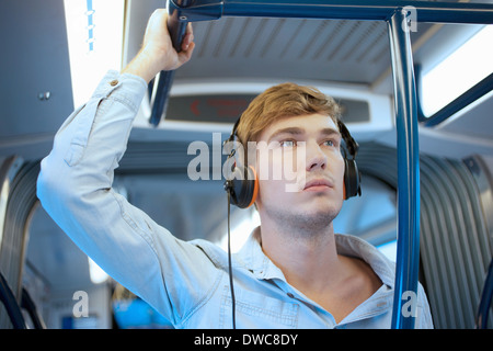 Junger Mann im Zug Wagen Kopfhörer anhören Stockfoto