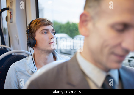 Junger Mann hören Kopfhörer auf Zug Stockfoto