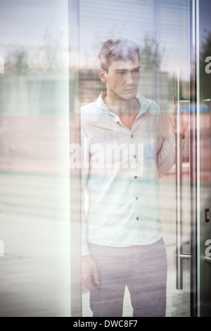 Unglückliche Jüngling hinter reflektierende Fenster Stockfoto