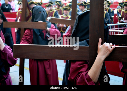 Büßer tragen große Kreuze in einer Prozession der Karwoche. Stockfoto