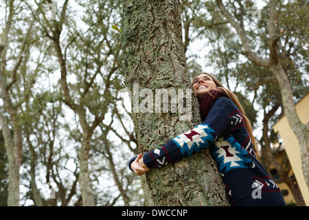 Junge Frau umarmt Baum im Wald Stockfoto