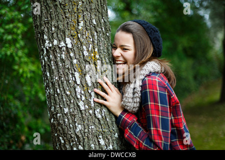 Teenager-Mädchen stützte sich auf Baum im Wald Stockfoto