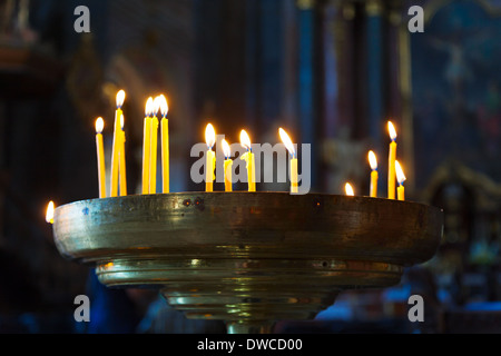 Mehrere große Kerzen in einem dunklen Raum in der Kirche Stockfoto