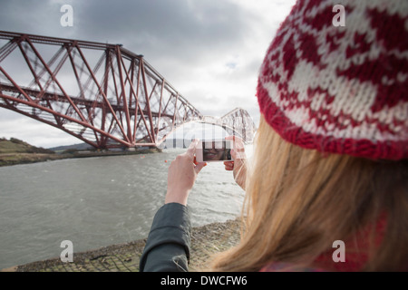 Eine junge Frau nehmen Foto von Forth Rail Bridge in Queensferry, in der Nähe von Edinburgh, Schottland Stockfoto