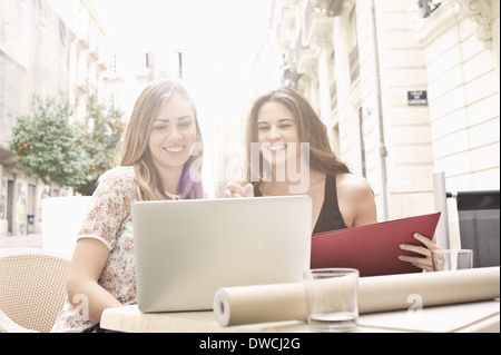 Zwei junge Freundinnen Blick auf Laptop am Bürgersteig Café, Valencia, Spanien