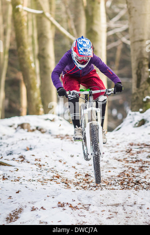 Junge weibliche Mountainbiken im Winterwald Stockfoto