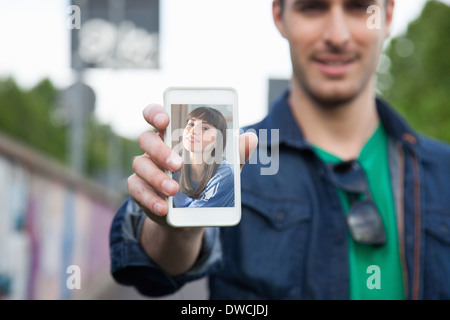 Junger Mann hält Smartphone mit Foto der Freundin Stockfoto