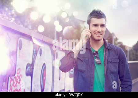 Junger Mann mit Smartphone mit leuchtenden Lichter kommen aus ihm heraus Stockfoto