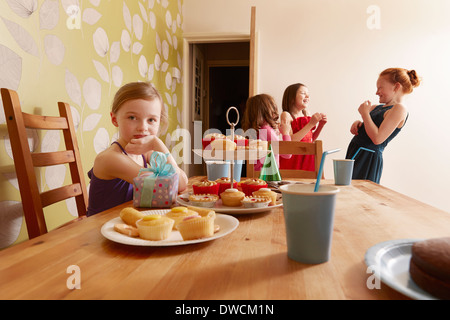 Mädchen am Tisch mit Party Essen, Freunde im Hintergrund Stockfoto