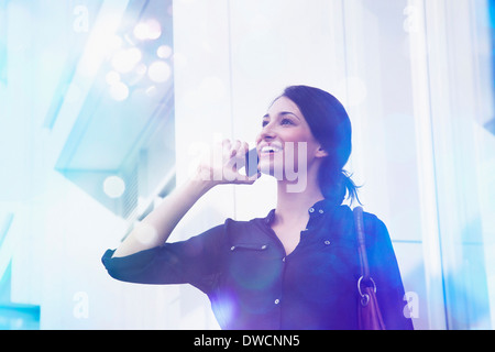 Junge Geschäftsfrau spricht am Smartphone mit Lichter kommen aus ihm heraus Stockfoto