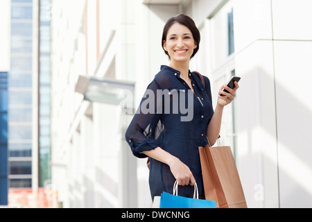Junge Geschäftsfrau mit Smartphone und Einkaufstaschen Stockfoto