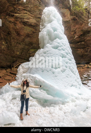 Frau steht Rieseneishöhle Kegel, der am Fuße des Wasserfalls Ash-Höhle, Hocking Hills State Park gebildet hat Stockfoto