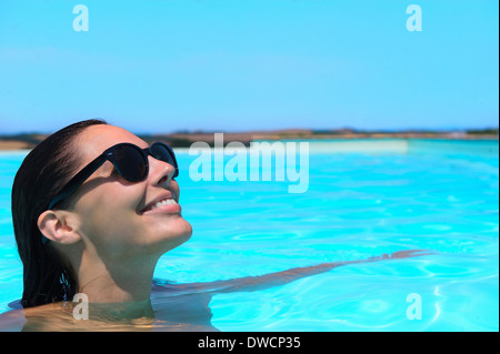 Mitte Erwachsene Frau mit Sonnenbrille entspannen im pool Stockfoto