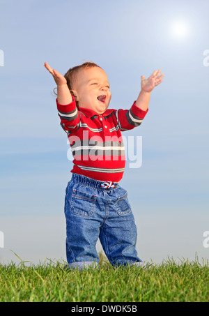 Babymädchen stehen auf dem Rasen und die Sonne genießen Stockfoto