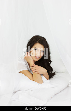 Schöne junge Frau im weißen Raum, mit entspannten Ausdruck, lange dunkle Haare Stockfoto