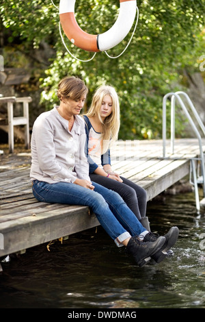 Mutter und Tochter sitzen am pier Stockfoto