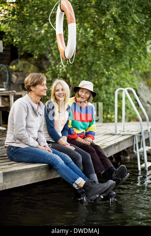 Drei Generationen Weibchen sitzen am pier Stockfoto