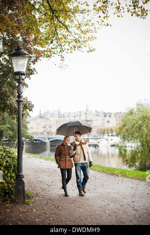 Junges Paar mit Regenschirm gehen auf der Straße im Herbst Stockfoto