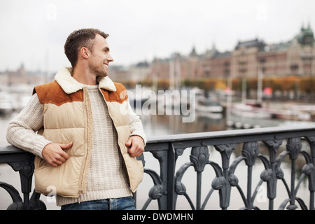 Junger Mann stützte sich auf Geländer im freien Stockfoto