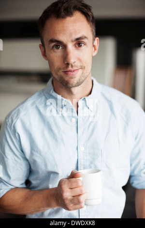 Porträt von zuversichtlich Geschäftsmann hält Kaffeetasse im Büro Stockfoto