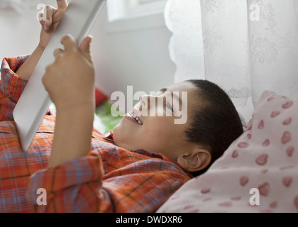 Junge mit digital-Tablette beim liegen im Bett Stockfoto