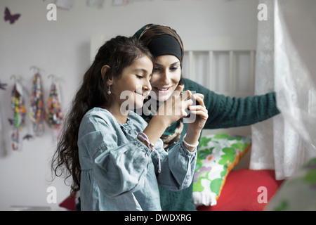 Mutter und Tochter betrachten Bilder vor der Kamera im Schlafzimmer Stockfoto