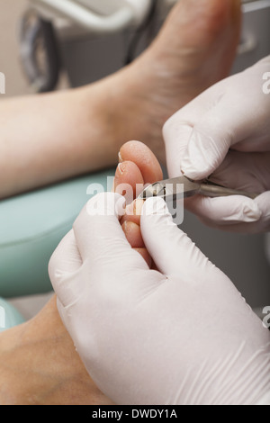 Eine Fußpflegerin die Betreuung von Frau Fuß - Nägel schneiden mit einem Zehennagel Clipper Stockfoto