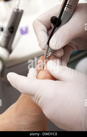 Eine Fußpflegerin kümmert sich Frau Fuß - Polieren der Nägel mit einem speziellen Werkzeug Stockfoto