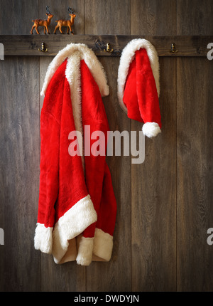 Santas Mantel und Hut aufhängen mit Rentier auf Sims Stockfoto