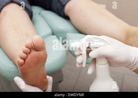 Fußpflegerin die Pflege des weiblichen Fußes - besprüht den Fuß einer Kundin mit einer lotion Stockfoto