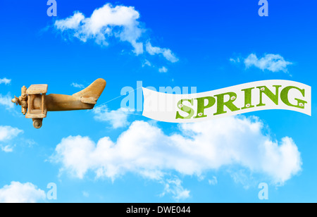 Vintage Holz Spielzeug Flugzeug fliegen in blauen Himmel ziehen einen Banner im Frühjahr bringen Stockfoto