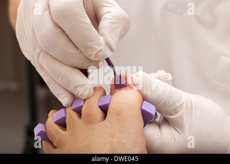 Fußpflegerin kümmert sich Frau Fuß - Malerei die Zehennägel Stockfoto