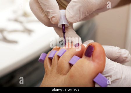 Fußpflegerin kümmert sich Frau Fuß - Malerei die Zehennägel Stockfoto