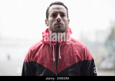 Sportlichen Mann in Jacke Musik über Kopfhörer hören Stockfoto