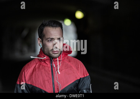 Sportliche nachdenklicher Mann in Jacke, Musik hören Stockfoto