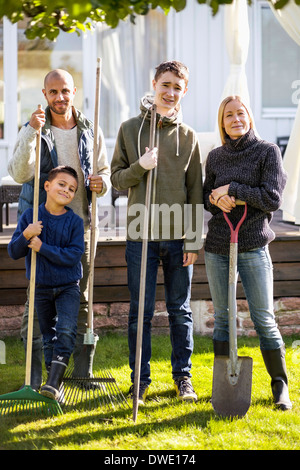 Porträt von zuversichtlich Familie mit Gartengeräten am Hof stehen Stockfoto