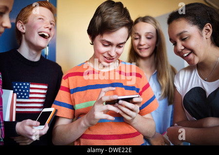 Glückliche Schüler mit Handys in der Schule Stockfoto