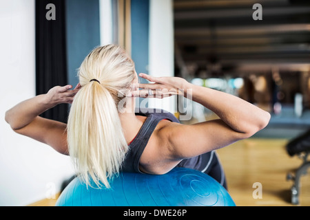 Junge Frau, die auf Fitness-Ball im Fitness-Studio trainieren Stockfoto