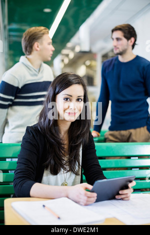 Porträt von weiblichen Studenten halten digital-Tablette mit Freunden im Hintergrund Stockfoto