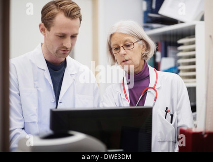 Leitende Ärztin mit männlicher Kollege mit Computer im Untersuchungsraum Stockfoto